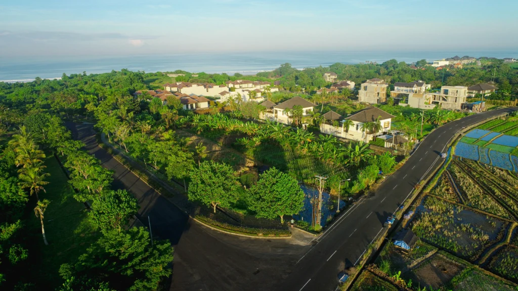 Aerial view of Ciputra Beach Resort surrounded by tropical greenery, rice fields, and ocean views, showcasing a tranquil and luxurious residential environment.